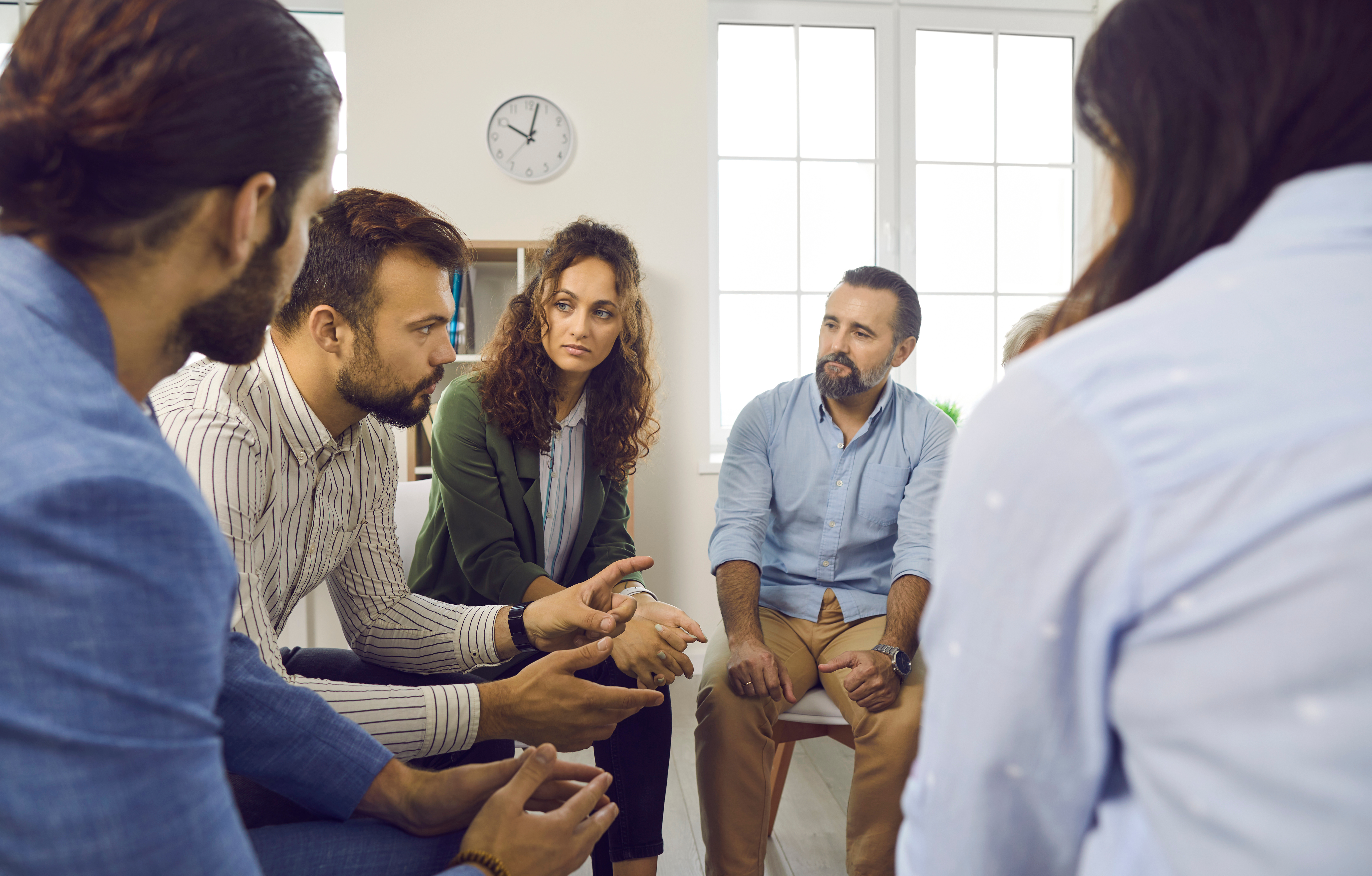 un groupe de 5 adultes discutent assis en rond